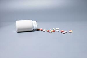 Pills spilling out of pill bottle  two-colored capsules pills  Medicines and prescription pills flat lay background. White medical pills and tablets spilling out of a drug bottle.Copy space for text photo