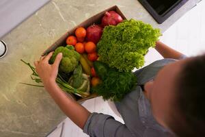 Top view woman received a box full of fresh groceries ordered online by home doorstep delivery. Food delivery service photo