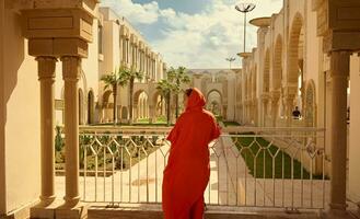 posterior ver de un hembra turista en tradicional auténtico marroquí ropa, visitando y admirativo hassan ii mezquita foto