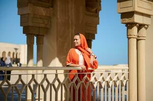 Gorgeous Middle Eastern Muslim woman with head covered in hijab and ethnic dress, smiles looking aside, Hassan II mosque photo