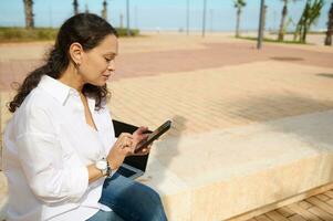 Young woman using smartphone checks social media content outdoors, messaging, browsing new app, online shopping, booking photo