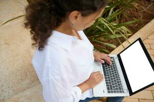 Top view business woman typing on laptop, remotely working. Adult student studying online. White mockup digital screen photo