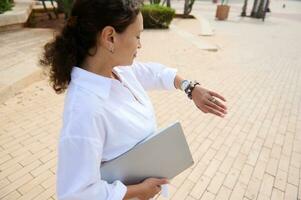 Middle aged businesswoman checking time on her wrist watch. Punctuality, time management, people, recruitment and career photo