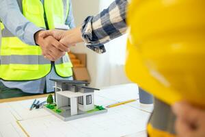 Architects and construction engineering handshake after meeting discuss structural blueprints calculate project completion. cooperation and handshake between of construction engineers and architects. photo