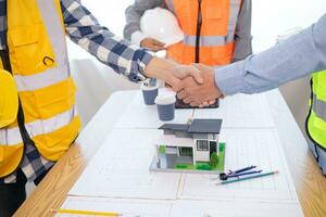Architects and construction engineering handshake after meeting discuss structural blueprints calculate project completion. cooperation and handshake between of construction engineers and architects. photo