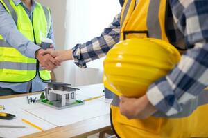 Architects and construction engineering handshake after meeting discuss structural blueprints calculate project completion. cooperation and handshake between of construction engineers and architects. photo