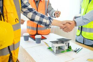 Architects and construction engineering handshake after meeting discuss structural blueprints calculate project completion. cooperation and handshake between of construction engineers and architects. photo