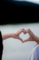 young woman and her friend raised their hands together to form heart shape to show their friendship love and kindness with their belief and power of faith in their friendship. concept of friendship photo