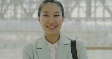 Slow motion portrait of ambitious Asian lady smiling standing in office building lobby and looking at camera. Successful career and business concept. video