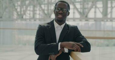 Joyful African American commuter standing in modern glass wall airport smiling waiting for business trip. Professional occupation and businessperson concept. video