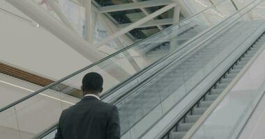 Slow motion of business team moving up in escalator in contemporary airport building talking enjoying trip. Teamwork and commuting concept. video