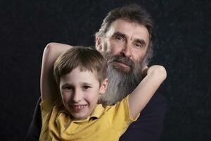 Portrait of a happy grandfather with a beard and grandson on a black background. photo