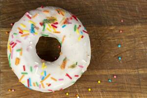 Creative sweet food. Glazed colorful donut on a wooden background. photo