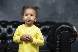 Portrait of a little playful African American girl in the room. photo
