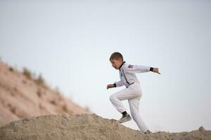 A young boy dressed as an American astronaut runs against the backdrop of the white mountains. photo