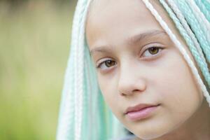 Fashionable little girl with multicolored African braids looks into the camera. photo