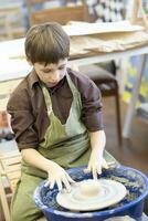 A little boy makes a clay product at a potter's wheel. photo