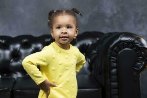 pequeño juguetón africano americano niña en amarillo ropa a hogar. foto