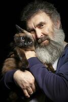 Portrait of an elderly man with a gray beard holding a cat. Man and pet. photo