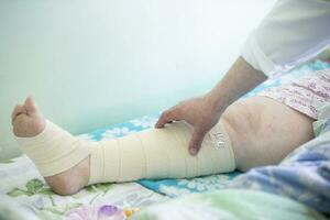 The doctor touches the patient's bandaged leg.Leg in bandages. photo