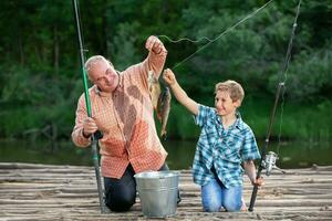 abuelo y nieto son pescadores con pescar varillas y atrapado pez. foto