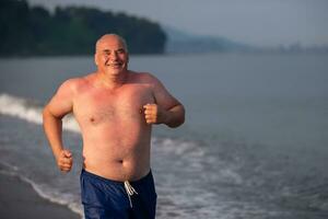 un mayor hombre de atlético construir es trotar a lo largo el orilla del mar.la hombre va en para Deportes. foto