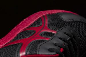 A fragment of a black sneaker with a red sole close up. Sneaker texture photo