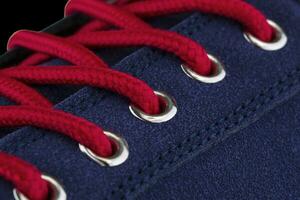 A fragment of a blue sneaker with red laces close up. Sneaker texture photo