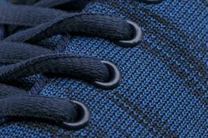 A fragment of a blue sneaker with red laces close up. Sneaker texture photo