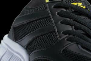 Fragment of a black sneaker with white sole close up. Sneaker texture photo
