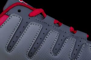 A fragment of a black sneaker with red laces close up. Sneaker texture photo