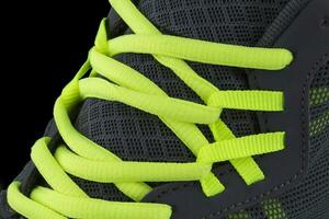 Fragment of black sneaker with green laces close up. Sneaker texture photo