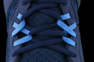 A fragment of a blue sneaker with red laces close up. Sneaker texture photo