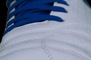 A fragment of a white sneaker with blue laces close up. Sneaker texture photo