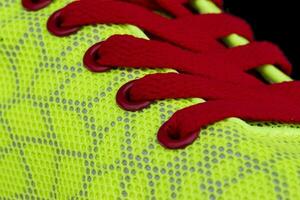 Fragment of a green sneaker with red laces close up. Sneaker texture photo