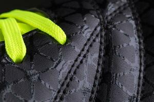 Fragment of black sneaker with green laces close up. Sneaker texture photo