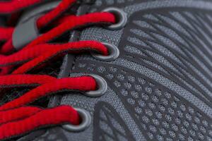 A fragment of a black sneaker with red laces close up. Sneaker texture photo