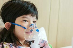 Sick little asian girl inhalation with nebulizer for respiratory treatment photo