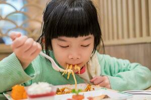 linda pequeño asiático niño niña comiendo comida foto