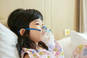 Sick little asian girl inhalation with nebulizer for respiratory treatment photo