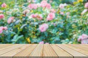 Empty wood table top with blur rose garden background for product display photo