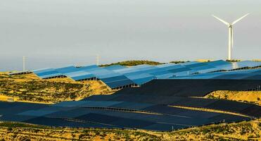 solar paneles en un ladera con viento turbinas foto