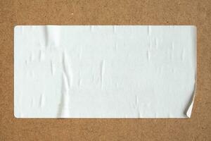 Blank white paper sticker texture on brown cardboard background photo