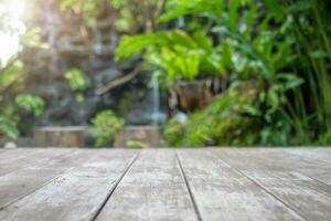 Empty wood table top with blur green tropical garden background for product display photo