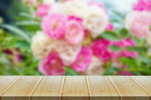 Empty wood table top with blur rose garden background for product display photo