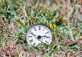 an old clock in the grass photo