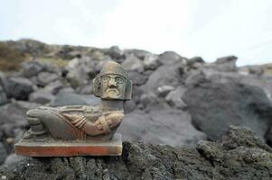 a statue of a man sitting on a rock photo