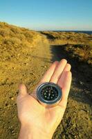 a person holding a compass on a dirt road photo