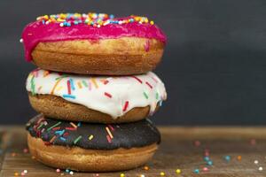 Lovely sweet food. Stack of glazed colorful assorted donuts with splashes on a gray background. photo