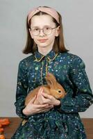 Portrait of a girl in glasses with a red rabbit. Child with a rabbit. photo